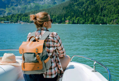 Traveller woman enjoying beautiful view of turquois lake and mountains sitting on sailing paddleboat