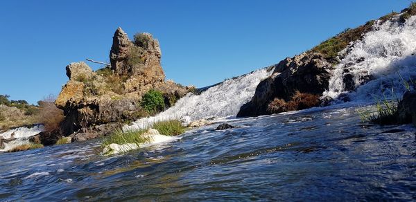 Rock formations in sea against clear blue sky