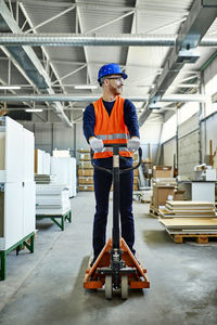 Worker riding on pallet jack in factory
