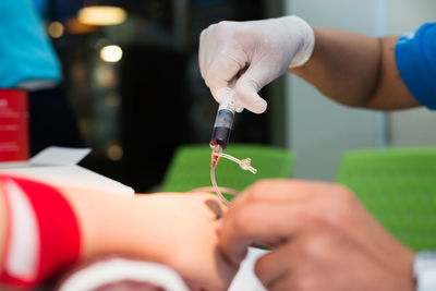 Cropped hands of nurse taking blood sample of patient at hospital