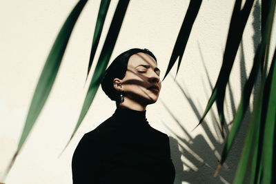 Portrait of young woman standing against plants