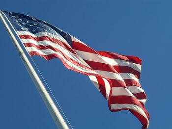 Low angle view of american flag against clear blue sky