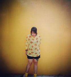 Full length of a girl standing against wall