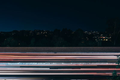 Light trails on street against sky at night