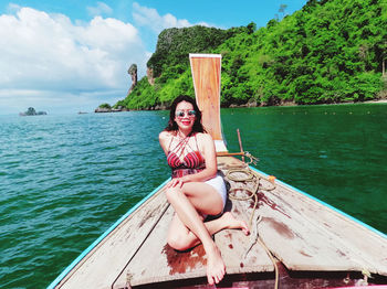 Portrait of woman sitting on boat in sea against sky chicken island, krabi, thailand