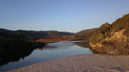 Scenic view of lake and mountains against clear blue sky