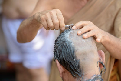 Midsection of barber shaving head of man