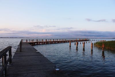 Pier over sea against sky during sunset