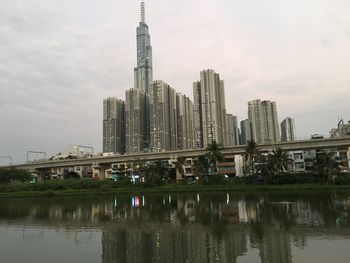 Reflection of buildings in lake against sky in city