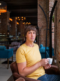 Man drinks coffee in cafe. loft designed interior and plush chairs. breakfast  away from home.