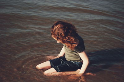 Rear view of woman sitting in sea