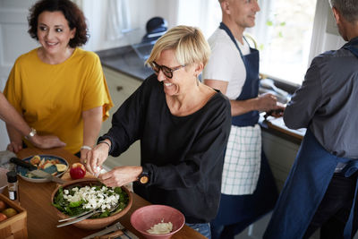 High angle view of happy friends preparing food together in kitchen at home