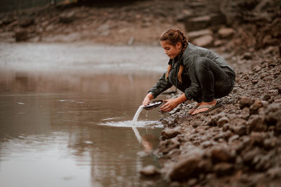 Side view of girl crouching at lake