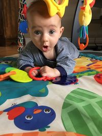 Portrait of cute boy with toy toys on floor at home