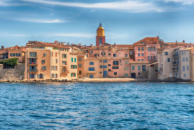 Buildings by sea against sky