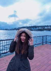 Portrait of beautiful young woman against river