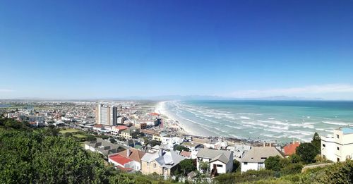 High angle view of town by sea against clear blue sky