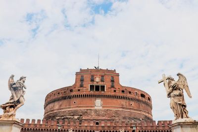 Low angle view of statue of building against cloudy sky