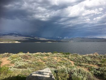 Scenic view of lake and mountains against cloudy sky