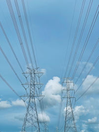 Low angle view of electricity pylon against blue sky