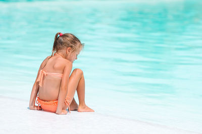 Full length of shirtless man sitting in swimming pool