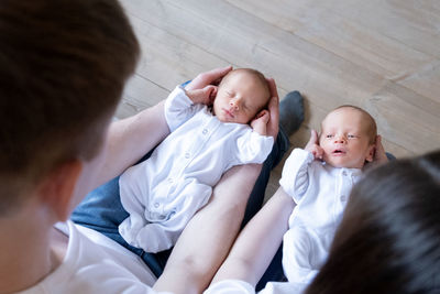 Newborn identical twins on the bed, on a parents hands. life style, emotions of kids. infant babies