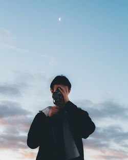 Man looking through binoculars against sky