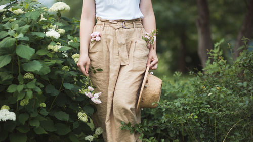 Midsection of woman standing by flowering plants