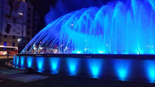 Illuminated city against blue sky at night
