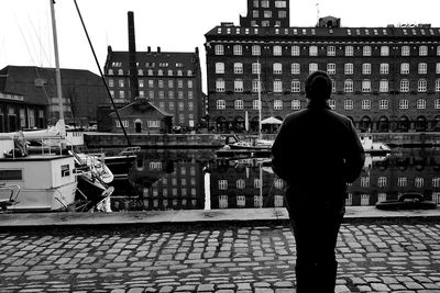 Rear view of silhouette man with city in background