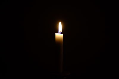 Close-up of illuminated candle in darkroom