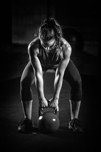 Woman lifting weight in darkroom