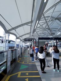 Rear view of people walking on railroad station platform