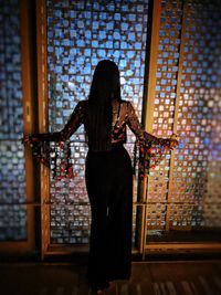 Rear view of woman standing against window