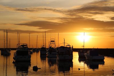 Boats moored at harbor against sky during sunset