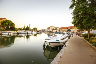 Boats moored at harbor against clear sky