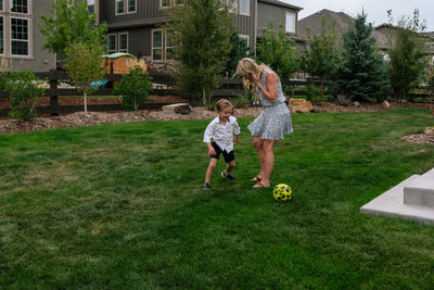 Little boy playing soccer with his mom in the yard