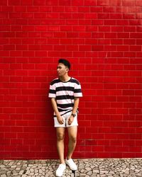 Full length of man standing against red brick wall