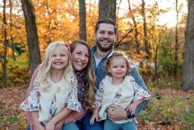 Portrait of happy family against trees during autumn