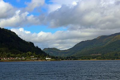 Scenic view of sea and mountains against cloudy sky