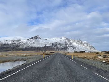 Road amidst snowcapped mountains against sky