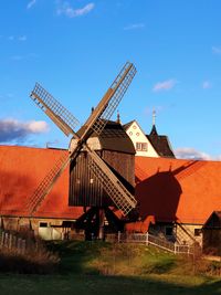 Traditional windmill on field against sky