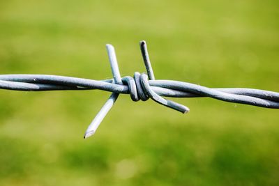 Close-up of barbed wire fence on field