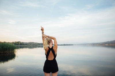 Woman standing by lake against sky