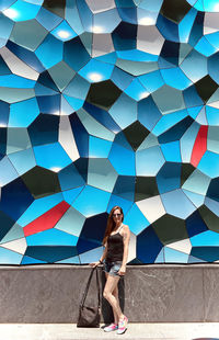 Full length of woman standing against multi colored wall