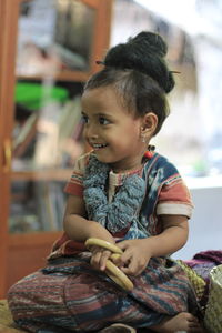 Smiling baby girl looking away while sitting on table