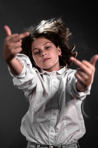 Portrait of girl standing against black background