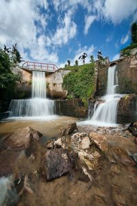 View of waterfall against cloudy sky