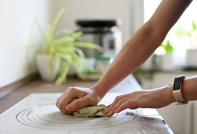 Close-up of woman kneading dough on table