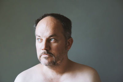 Close-up of shirtless man against gray background